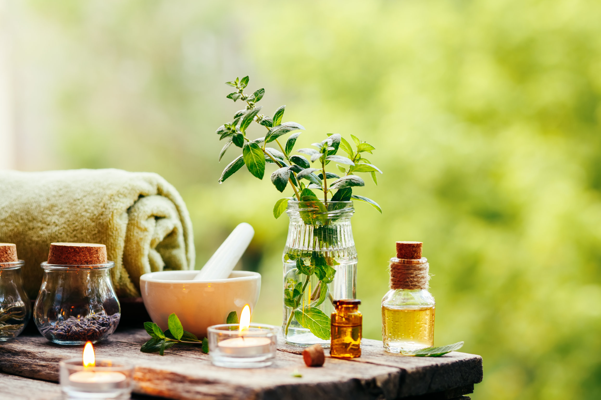 Spa background with essential oil, fresh peppermint and towel on wooden table outdoors. Selective focus.